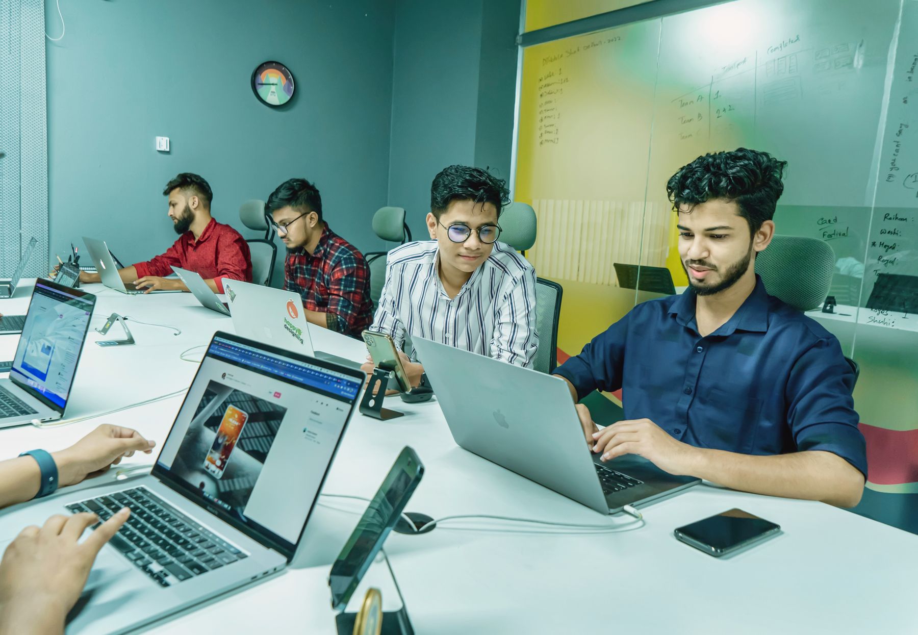 A Pakistani software team at work on laptops in an open office